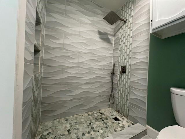 bathroom featuring a tile shower and toilet