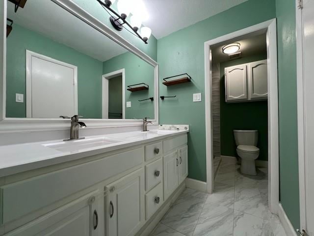 full bath featuring marble finish floor, a sink, toilet, and double vanity