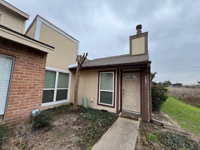 doorway to property with a chimney and brick siding