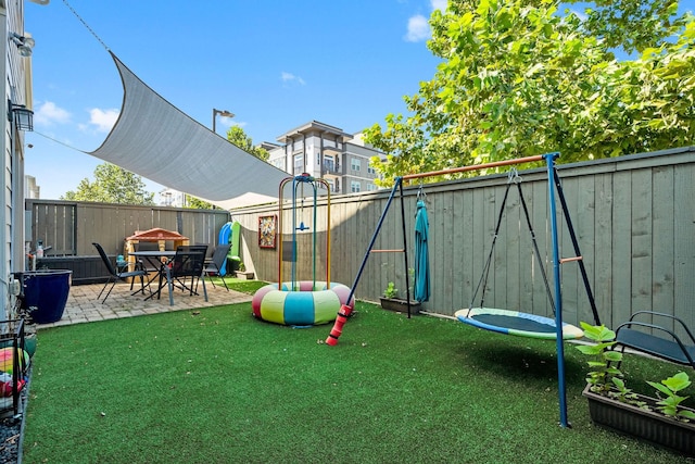 view of jungle gym featuring a fenced backyard, a lawn, and a patio