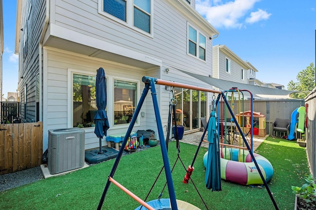 view of play area with a fenced backyard, a lawn, and central air condition unit