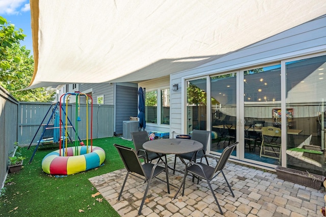 view of patio with outdoor dining area, a fenced backyard, a playground, and central AC