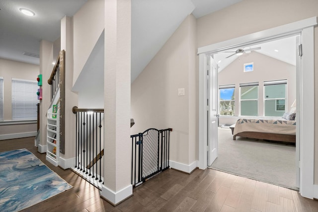 hall featuring dark wood finished floors, lofted ceiling, visible vents, an upstairs landing, and baseboards