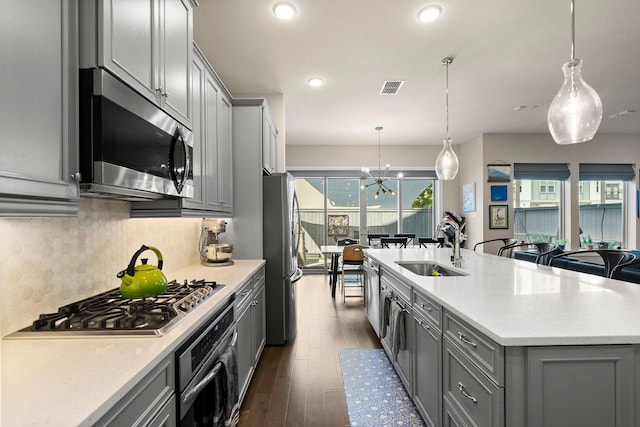 kitchen with stainless steel appliances, visible vents, decorative backsplash, gray cabinetry, and a sink