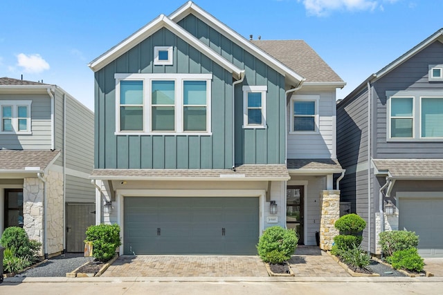 view of front of property with board and batten siding, decorative driveway, a shingled roof, and a garage