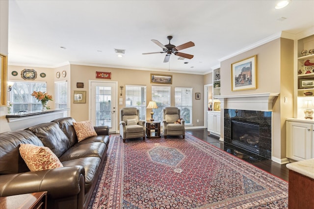 living area featuring visible vents, a tile fireplace, dark wood-style floors, crown molding, and built in shelves