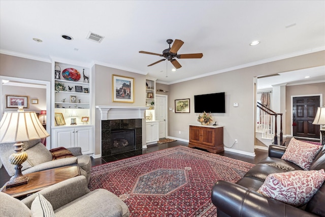 living area with a tile fireplace, visible vents, baseboards, dark wood finished floors, and crown molding