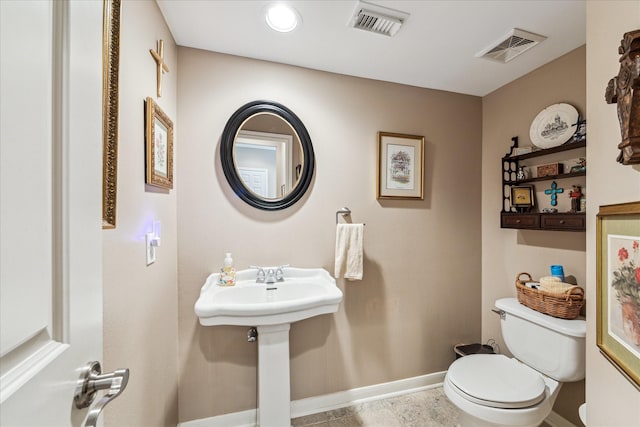 half bathroom with baseboards, visible vents, a sink, and toilet