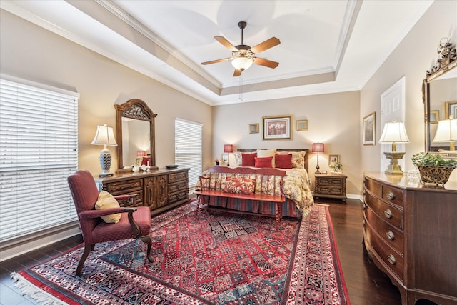 bedroom featuring baseboards, a raised ceiling, a ceiling fan, ornamental molding, and wood finished floors