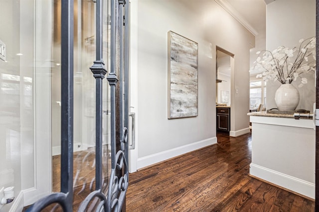 entryway with crown molding, baseboards, and dark wood-style flooring