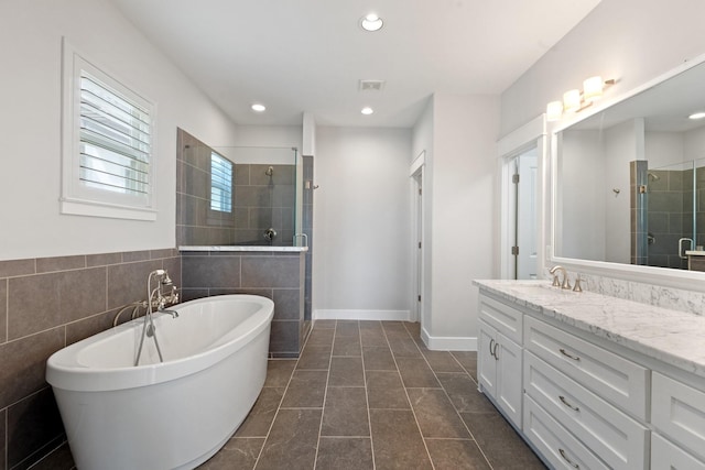 full bathroom with recessed lighting, a stall shower, vanity, a freestanding tub, and baseboards