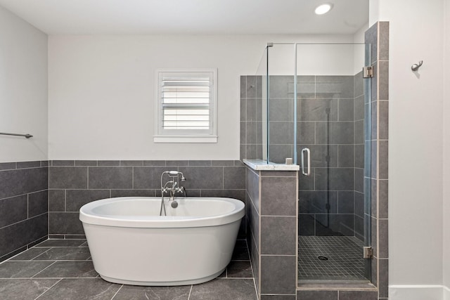 full bath with a stall shower, a soaking tub, wainscoting, and tile walls