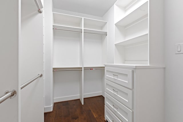 walk in closet with dark wood-style floors