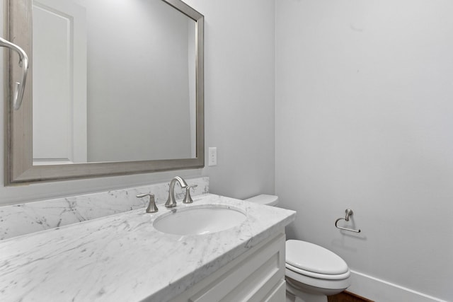 bathroom with toilet, baseboards, and vanity