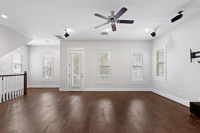 spare room with a ceiling fan, visible vents, dark wood finished floors, and baseboards