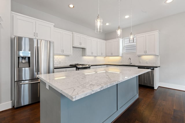 kitchen with stainless steel appliances, dark wood-type flooring, a sink, and light stone countertops