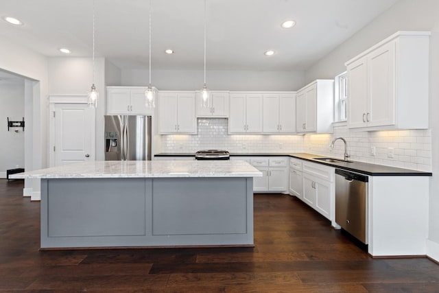 kitchen featuring dark wood-style flooring, appliances with stainless steel finishes, white cabinets, a sink, and a kitchen island