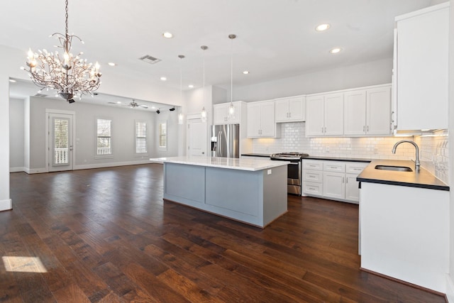 kitchen featuring visible vents, decorative backsplash, appliances with stainless steel finishes, open floor plan, and a sink