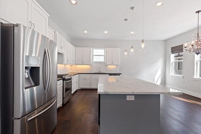 kitchen with stainless steel appliances, a sink, backsplash, a wealth of natural light, and a center island