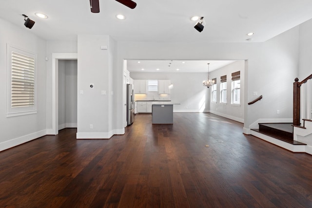 unfurnished living room with dark wood-style floors, recessed lighting, stairway, and baseboards