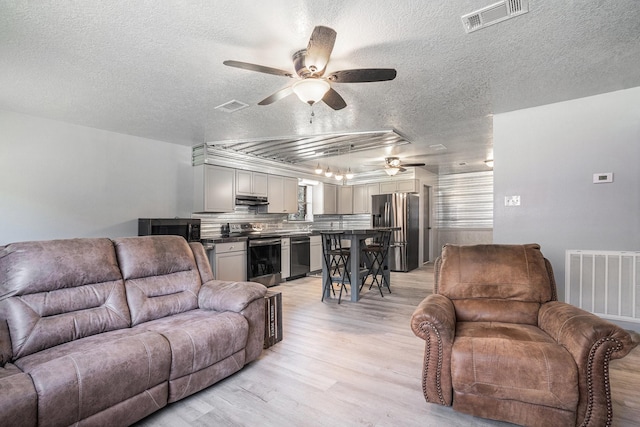 living area featuring a ceiling fan, visible vents, and light wood-type flooring