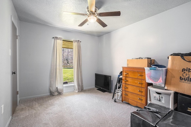 living area featuring baseboards, carpet, ceiling fan, and a textured ceiling