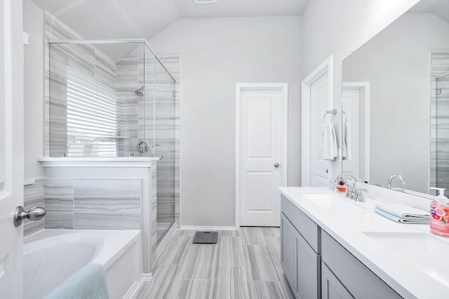 bathroom with double vanity, a garden tub, vaulted ceiling, a shower stall, and a sink