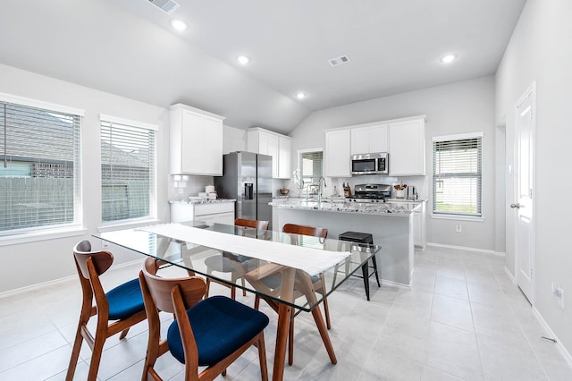 kitchen with light tile patterned floors, a kitchen island with sink, stainless steel appliances, and decorative backsplash