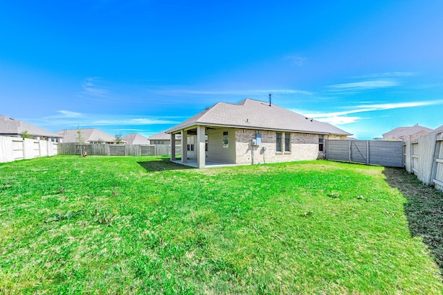 rear view of property featuring a patio area, a fenced backyard, a lawn, and brick siding