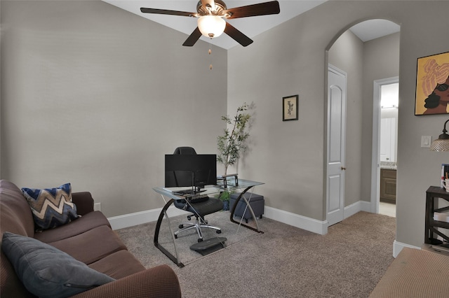 home office featuring baseboards, arched walkways, ceiling fan, and carpet flooring