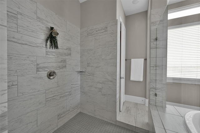 bathroom with a tile shower and baseboards