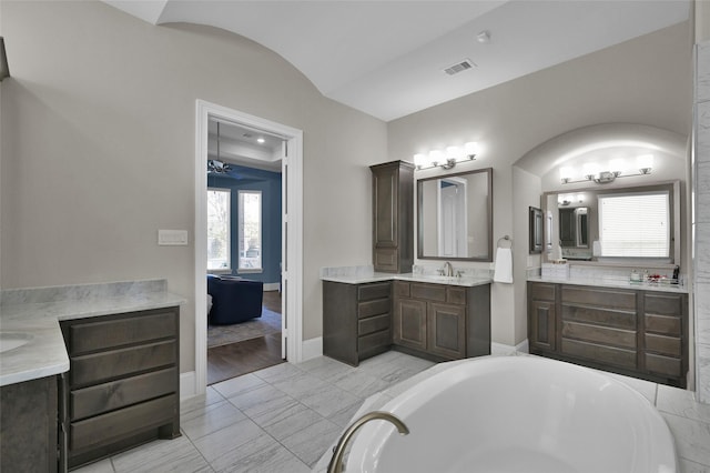 bathroom with a bathtub, marble finish floor, two vanities, visible vents, and a sink