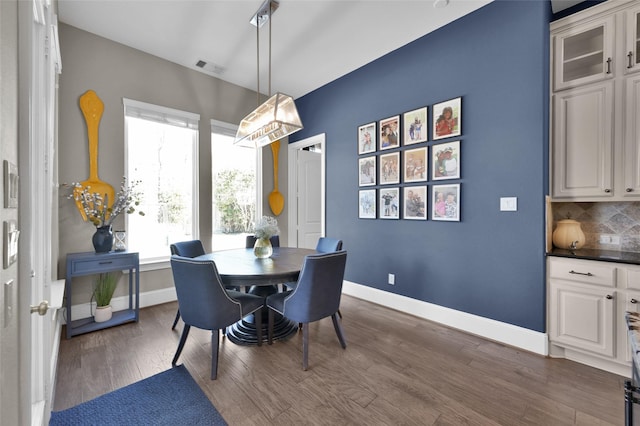 dining area with baseboards, visible vents, and dark wood-type flooring