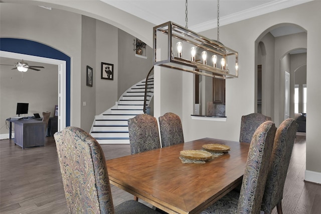 dining area with arched walkways, ceiling fan, wood finished floors, stairway, and crown molding