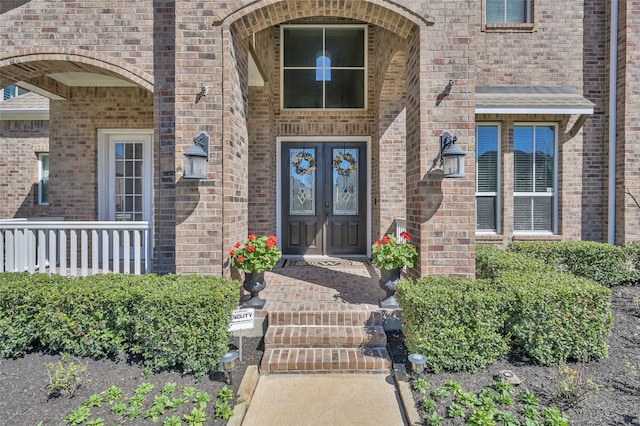 view of exterior entry featuring french doors and brick siding