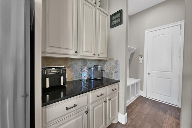 kitchen featuring baseboards, white cabinets, stainless steel refrigerator, dark wood-style flooring, and backsplash