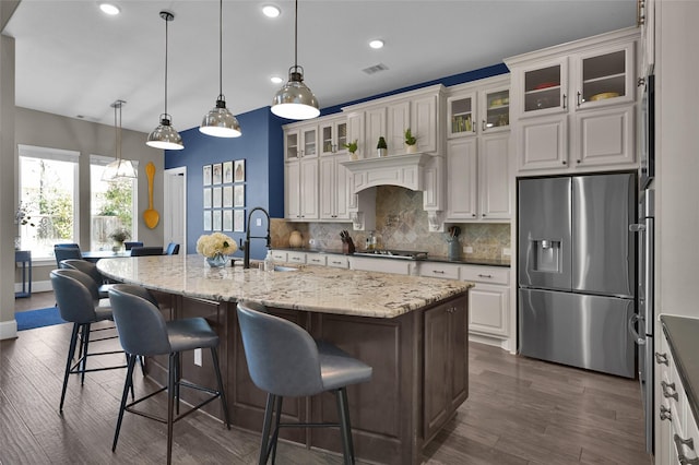 kitchen with visible vents, decorative backsplash, stainless steel fridge with ice dispenser, gas cooktop, and a sink