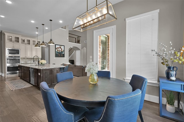 dining room featuring arched walkways, dark wood-style flooring, baseboards, and recessed lighting