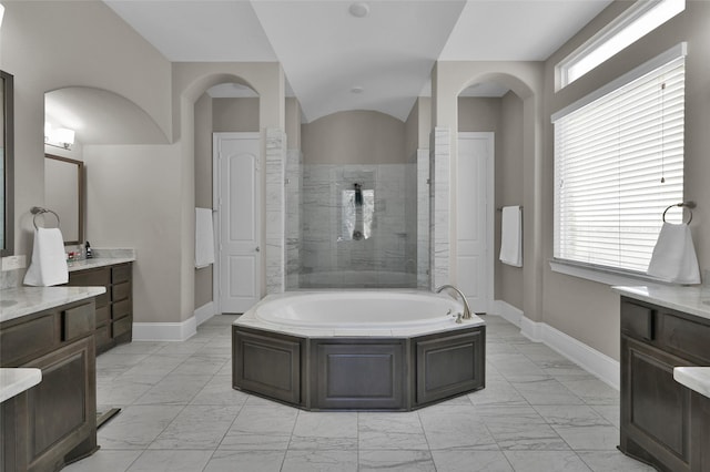 bathroom with marble finish floor, baseboards, and a bath