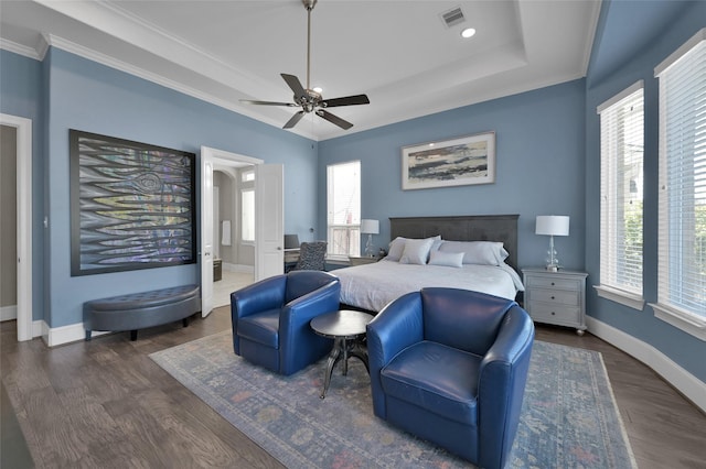 bedroom with wood finished floors, multiple windows, a raised ceiling, and visible vents