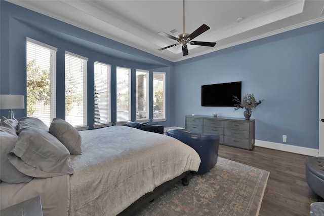 bedroom featuring ornamental molding, a tray ceiling, baseboards, and wood finished floors