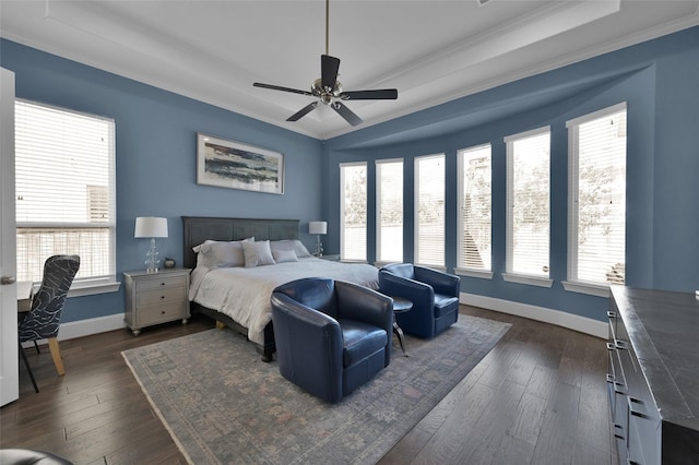 bedroom with ceiling fan, dark wood-type flooring, baseboards, ornamental molding, and a raised ceiling