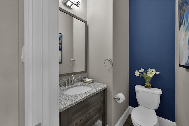 bathroom with baseboards, vanity, and toilet