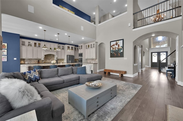 living room featuring baseboards, visible vents, arched walkways, and dark wood-style flooring