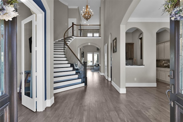 entryway featuring baseboards, ornamental molding, stairway, dark wood-style floors, and an inviting chandelier