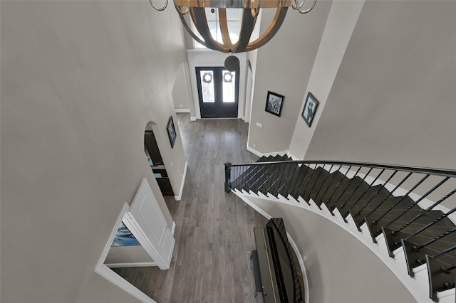 entryway featuring arched walkways, french doors, stairway, wood finished floors, and baseboards