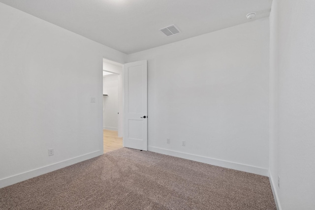 empty room featuring visible vents, light carpet, and baseboards