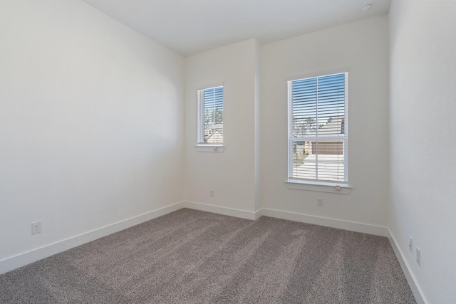 carpeted spare room with plenty of natural light and baseboards