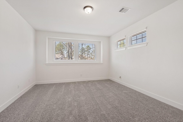 carpeted spare room featuring baseboards, visible vents, and a healthy amount of sunlight