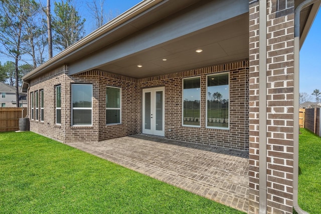 rear view of house with brick siding, a lawn, a patio area, and fence